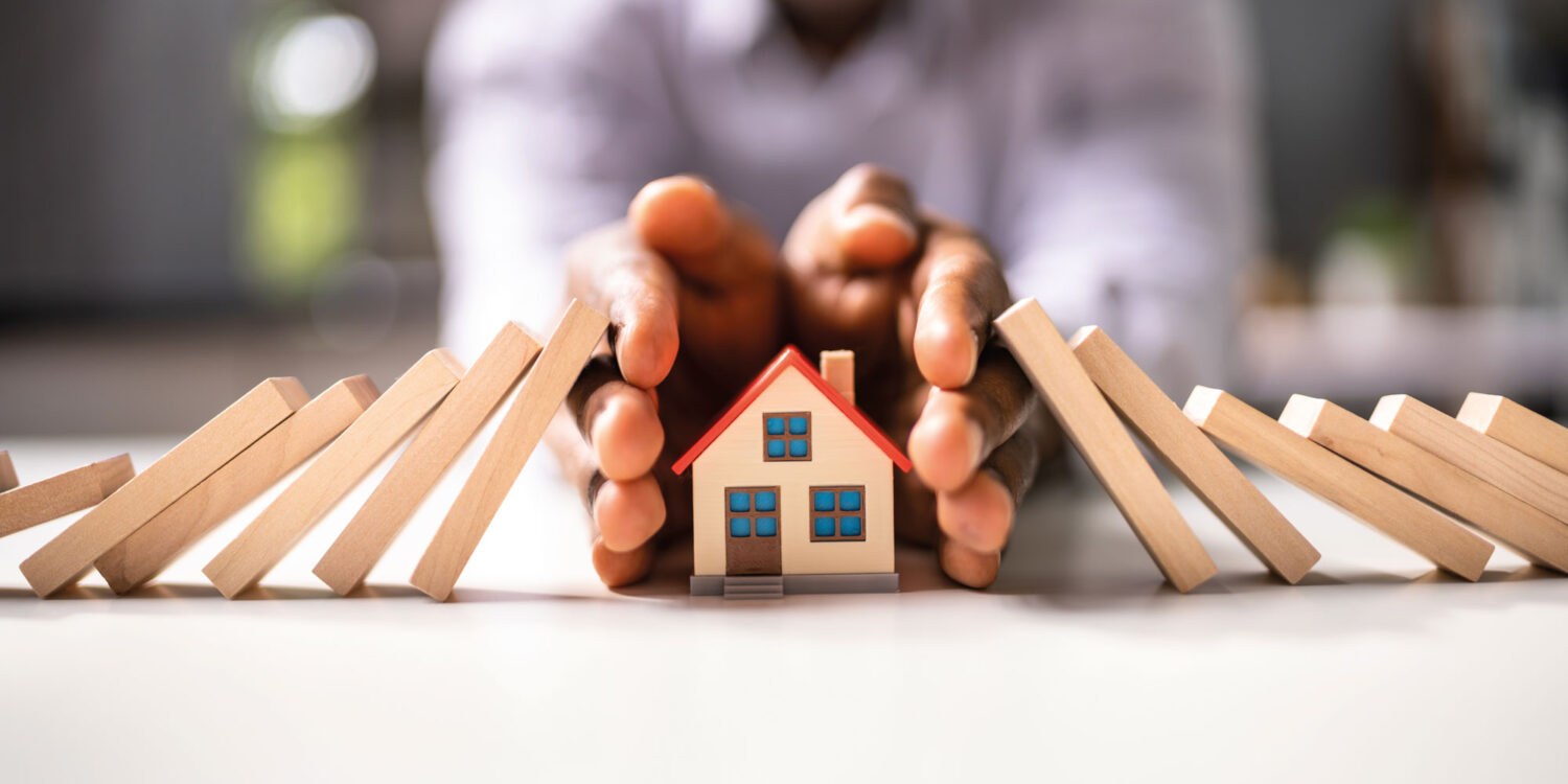 Hands shielding a toy house