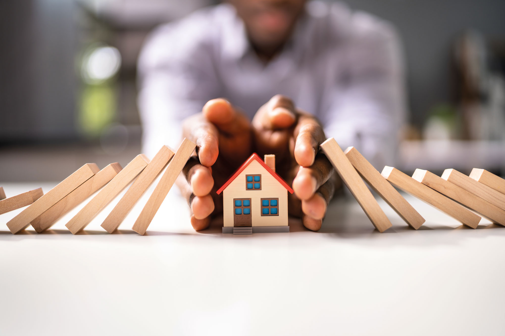 Hands shielding a toy house